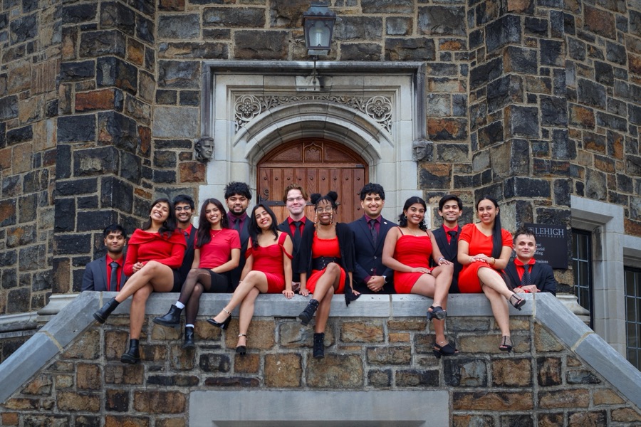 The bhangra team in red and black sitting on a stone wall at Lehigh