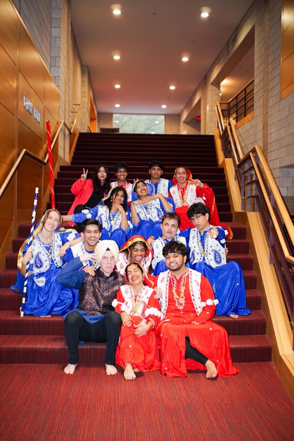 The bhangra team in traditional outfits sitting together on a staircase